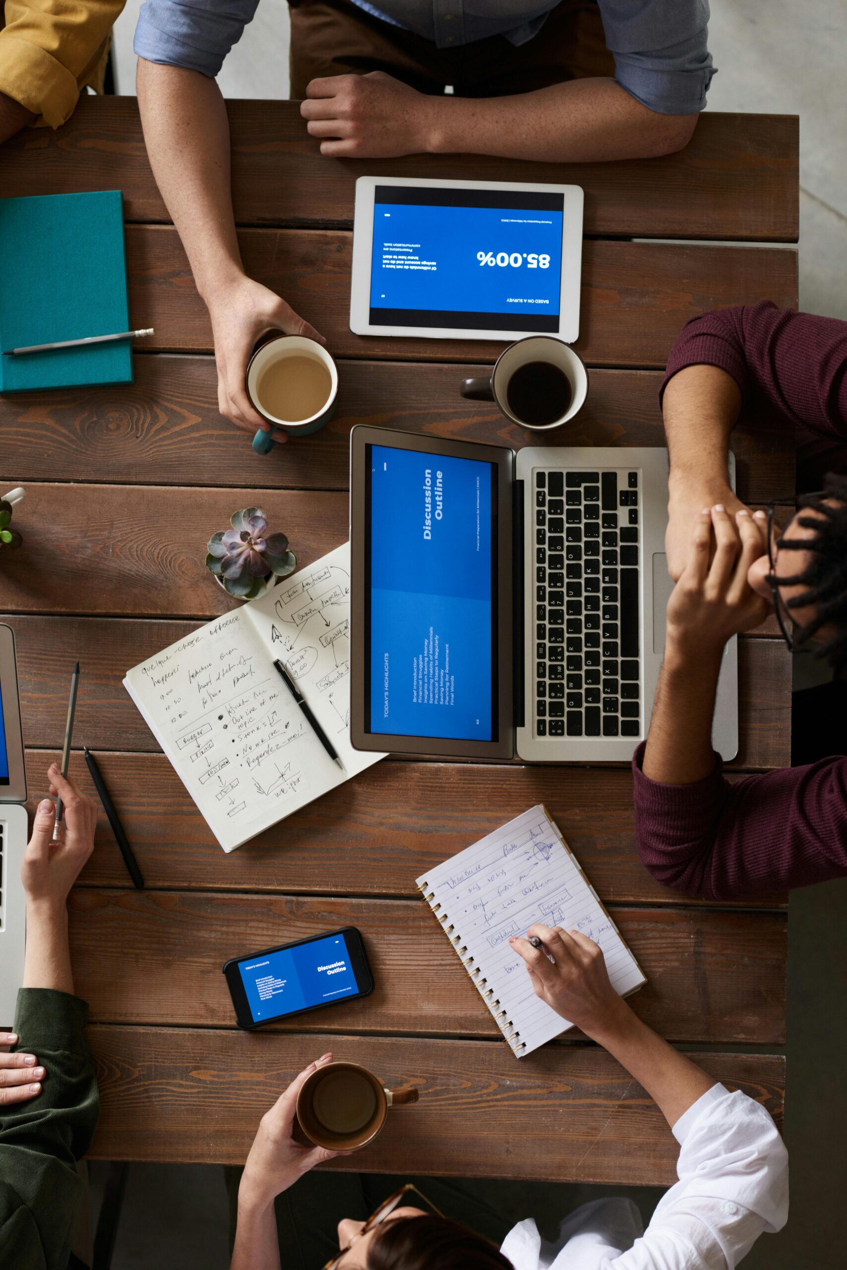 Software Group of coworkers discussing business strategies with laptops and tablets in a modern office setting.
